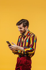 A man on a yellow background looks into a smartphone
