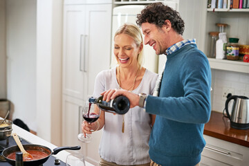 Couple, stove and pour wine for drinking in home, love and care for food or meal in kitchen. Happy...