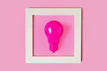 Pink light bulb in white frame on pink background - Concept of woman and creativity