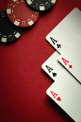 A playing card combination of four aces in poker or four of a kind or quads and chips on a red...
