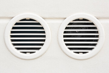 White plastic ventilation grille for internal air conditioner against a plaster wall - Double grille for air intake from outside and hot air evacuation from inside