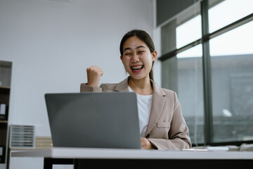 Overjoyed charming excited asian business woman worker using laptop working in office, feeling...