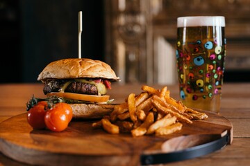 Delicious hamburger and french fries on a wooden board with cherry tomatoes