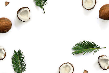Coconut ( Cocos nucifera ) with halfs and palm leaves on a white background with space for text. Top view, flat lay