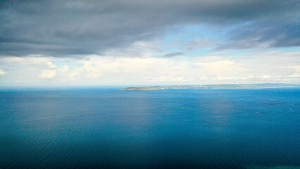 Scenic view of dark cloudy sky over clear blue endless ocean