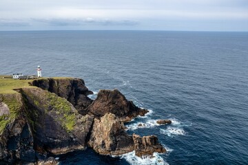 Aerial shot of a lighthouse on the edge of big cliffs and the Atlantic Ocean in Donegal Ireland