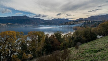 Beautiful view of trees on a hill among a bright blue lake in the mountains