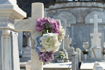 White marble cross with french hydrangea flowers in the graveyard