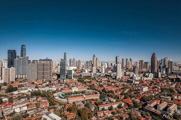 High-angle view of city full of skyscrapers under the blue sky. - obrazy, fototapety, plakaty