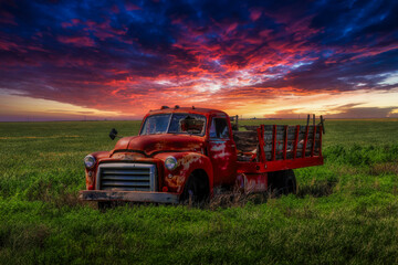 Rustic, red vintage truck sits under a vibrant Kansas sunset