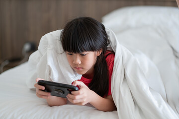 kid is addicted to tablet, little girl playing smartphone, kid use telephone, watching cartoon - 781192463