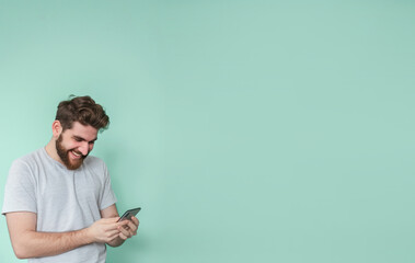 A man on a turquoise background looks at the phone
