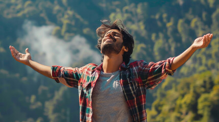 Portrait of a free happy Indian man with open arms enjoying life in meadows and nature background , young joyful asian male with good mental health