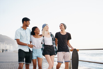 Group, friends and smile for walk on promenade by ocean for diversity, bonding and talking on holiday. Men, women or gen z people with conversation, happy and outdoor on boardwalk by sea on vacation