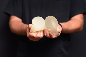 The doctor is clutching breast augmentation implants in his hands