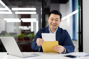 Professional male in a suit with a beaming smile holding an envelope, concept of good news or...