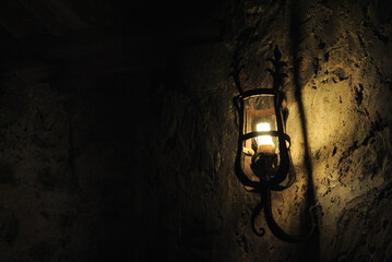 Close Up of Old Illuminated Iron Lamp in Dark Room of Ancient Brick Castle