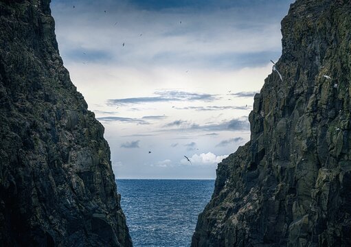 Beautiful shot of a seascape taken from in between two cliffs under the clouds