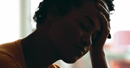 Depressed young woman suffering from mental illness. One black person overwhelmed by stress and quiet despair, close-up face holding head with hand