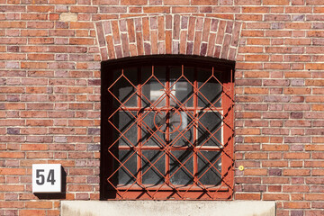 Altes fenster mit verzierten Fenstergitter und Hausnummernschild an einer roten Backsteinmauer, Wilhelmshaven, Niedersachsen, Deutschland