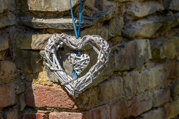 Closeup of wicker heart hanging from rocks - obrazy, fototapety, plakaty