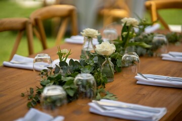 Wooden festive table on the street on a sunny day decorated with small flowers