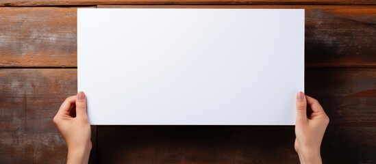 Person holding blank sheet on wooden surface - Powered by Adobe