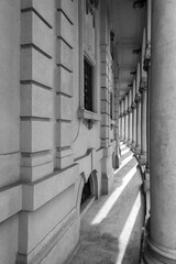 Black and white of curved arcade wall and a line of stone poles