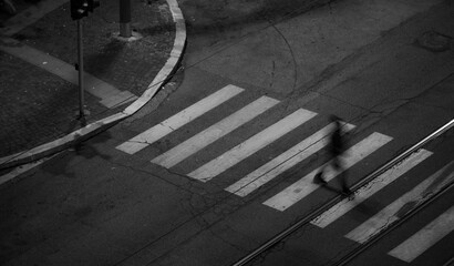 Long exposure grayscale of a person passing a street during the nighttime