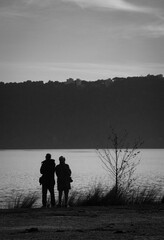 Beautiful shot of two people standing at the shore of lake