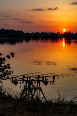 Fishing adventures, carp fishing. Angler, at sunset, is fishing with carpfishing technique. Camping on the shore of the lake.Carp Fishing Sunset