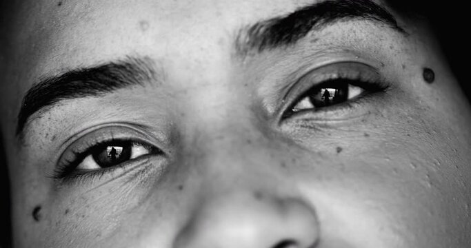 Intense macro close-up face of one young black woman facial eyesight features in monochrome, black and white gaze at camera