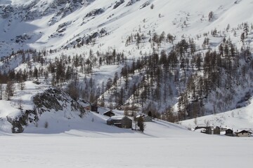Fototapeta na wymiar Mountain cabins covered with snow in Simplon Pass on a sunny winter day, Switzerland