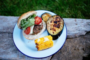 Plate with a homemade barbecue burger, eggplant, and corn