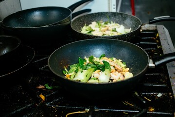 Closeup shot of pans with cooking stir fry prawn curry