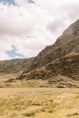 Vertical shot of a grass field with a mountain in the background on a sunny day