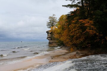 Beautiful autumn landscape with bright colored trees at the coast on a stormy day