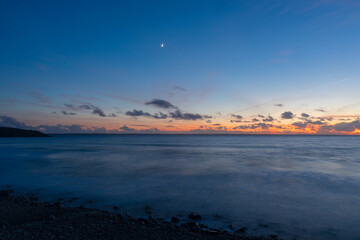 La quiétude règne en mer d'Iroise après le coucher du soleil, lors d'une longue pose où le ciel et l'océan fusionnent dans une symphonie de calme et de beauté.
