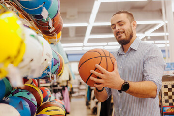 Young man chooses a basketball ball in a sports store