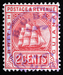Ukraine, Kiyiv - February 3, 2024.Postage stamps from BRITISH GUIANA.A stamp printed in British Guiana shows frigate and Latin phrase Damus petimusue vicissim, circa 1876.Philately.