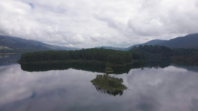 Drone shot of Colombian forests in the town of Neusa with reflection in lake under cloudy sky