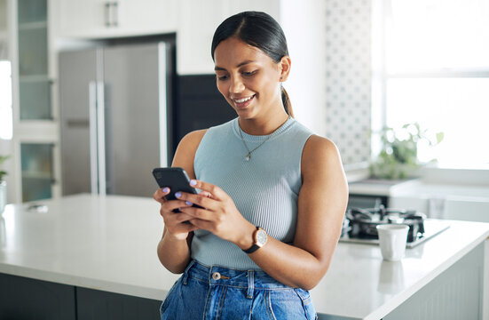 Smile, phone and woman in kitchen networking on website, internet or mobile app at home. Technology, happy and young female person typing online email on cellphone by counter in modern apartment.