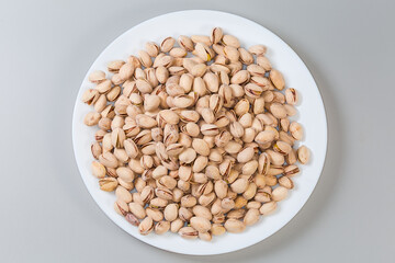 Roasted pistachio nuts on dish on gray background, top view - 781234663