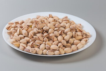 Roasted pistachio nuts on dish on gray background, side view - 781234664