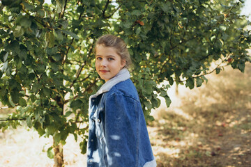 teenage girl with blue eyes and blond hair in an autumn garden. the girl near the trees with yellow...