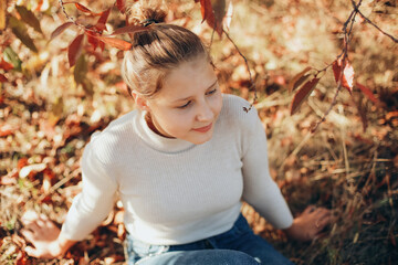 teenage girl in the autumn garden. the girl near the trees with yellow leaves is autumn time. portrait of a girl with yellowed leaves