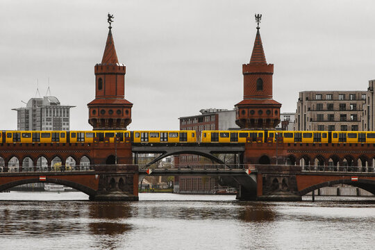 Yellow Berlin metro cars moving along the red brick historic bridge