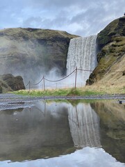 A Impressive waterfall in Skogafoss Iceland, with reflections in the water and on a cloudy day. vertical photo