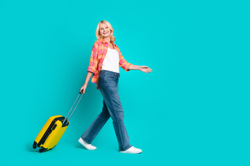 Photo of cheerful cute retired woman wear plaid stylish clothes walk empty space isolated on cyan color background