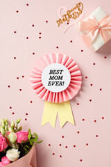 Best mom ever rosette, gift box, bouquet of flowers, confetti on pink background. Flat lay, top view.
